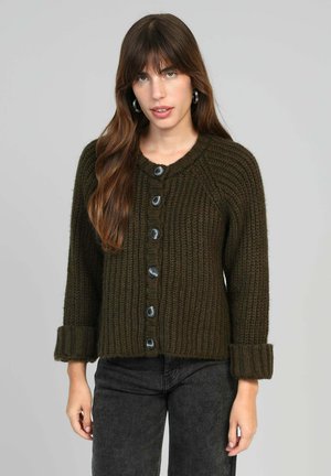 Cardigan tricoté vert foncé avec un col rond, texture côtelée et six grands boutons noirs sur le devant. Les poignets sont repliés.