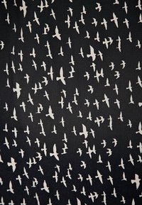 Tissu noir avec un motif répétitif d'oiseaux blancs dans différentes poses de vol, créant un effet visuel texturé et dynamique.