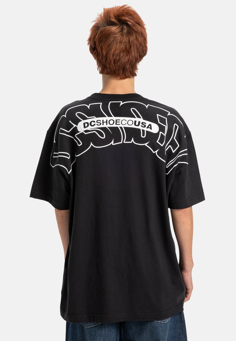 Černé bavlněné oversized tričko s výrazným bílým potiskem na zádech, kulatým výstřihem a krátkými rukávy. Neformální design s volným střihem.