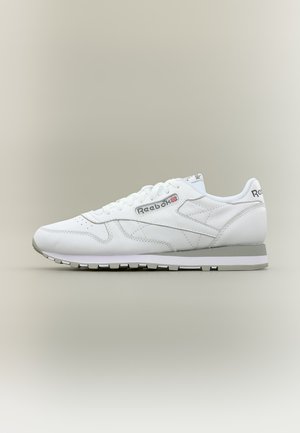 Бял кожен спортен обувки Reebok със сиви акценти, връзки и гумена подметка, показани в страничен профил на неутрален фон.