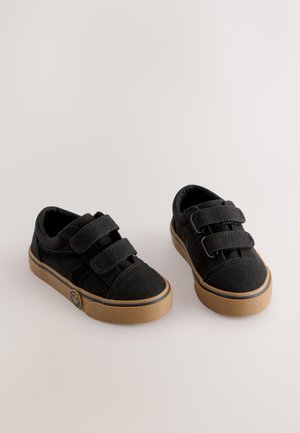 Czarne płócienne buty na gumowej podeszwie z dwoma rzepami, zaokrąglonymi noskami i logo po boku. Gładka faktura i prosty design.