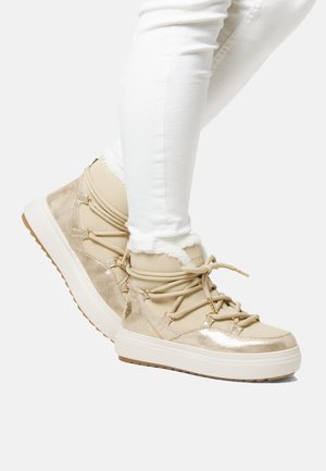 Beige High-Top-Sneaker mit glänzender Wellenstruktur, weichem Fellfutter und beigen Schnürsenkeln über einer weißen Mittelsohle und Gummisohle.