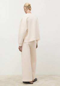 Ensemble de loungewear rose clair comprenant un sweat-shirt court et un pantalon large. Tissu doux avec une texture lisse et un design minimaliste.