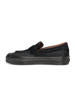 Zapatilla deportiva negra de tipo slip-on con parte superior de ante, suela de goma de perfil bajo y una tira al estilo mocasín penny loafer en la parte superior, vista de lado.