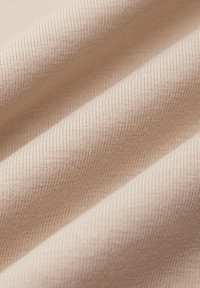 Jasno beżowa tkanina o prążkowanej fakturze, z miękkimi, gładkimi fałdami i subtelnym połyskiem, idealna do odzieży lub tapicerki.