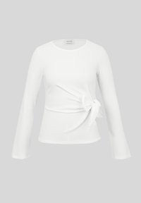 Λευκό μπλουζάκι με μακριά μανίκια, στρογγυλή λαιμόκοψη και λεπτομέρεια δεσίματος στο πλάι στη μέση, εμφανίζεται σε απλό γκρι φόντο.