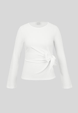 Biała bluzka z długim rękawem, okrągłym dekoltem i wiązaniem po boku w talii, prezentowana na jednolitym szarym tle.
