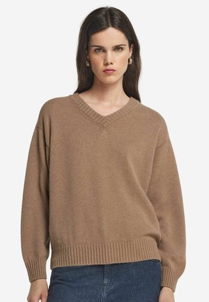 Brun strikket sweater med v-hals, ribbet kant og lange ærmer. Teksturen er blød og let løstsiddende.