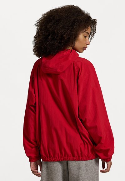 Κόκκινο, ελαφρύ μπουφάν με κουκούλα, ελαστικές μανσέτες και στρίφωμα. Διαθέτει άνετη εφαρμογή και λεία, ελαφρώς γυαλιστερή υφή.
