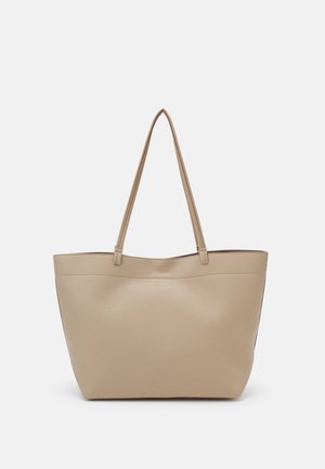 Sac tote beige texturé avec longues anses, forme rectangulaire et ouverture en haut, présenté sur un fond clair uni.