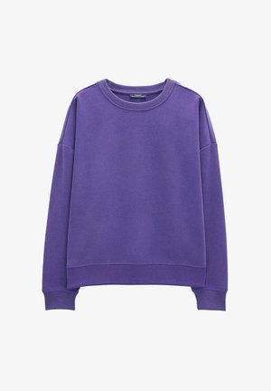 Fioletowy sweter z miękkiego materiału. Posiada okrągły dekolt, opadające ramiona oraz ściągacze na mankietach i u dołu. Prosty design, bez wzorów.