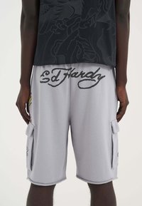 Gray cargo shorts with a relaxed fit, featuring a large “Ed Hardy” logo, side pockets, and minor graphic accents on the fabric.