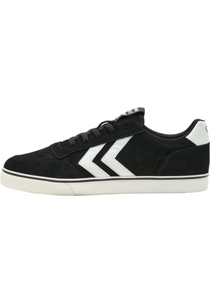 Sorte ruskinds sneakers med en hvid gummisål, der har to hvide chevronstriber på siden og sorte snørebånd.