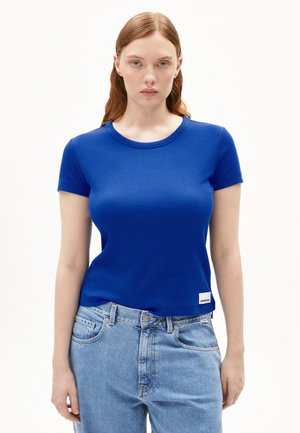 Blauw geribbeld T-shirt met korte mouwen en een ronde halslijn, gedragen met lichtblauwe denim jeans. Etiket zichtbaar linksonder.