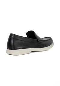 Black leather slip-on shoe with a rounded toe, minimal stitching, and a contrasting white rubber sole. Smooth texture with a casual design.