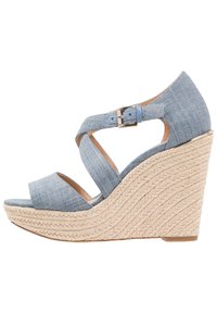 Sandały na koturnie z denimu z krzyżującymi się paskami i regulowanym zapięciem. Pleciona rope w śródstopiu dodaje tekstury, w jasnoniebieskim kolorze i z odkrytymi palcami.