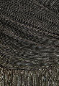 Czarna sukienka z cienkiego, ściśle plisowanego materiału z metalicznymi nitkami. Wielowarstwowe frędzle na dole dodają tekstury i detali.