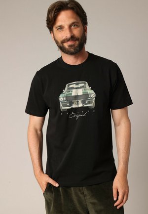 Zwarte katoenen t-shirt met een grafische afbeelding van een groene vintage auto en witte strepen op de voorkant, met de tekst "DEELUXE Original" eronder.