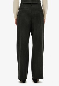 Pantalones de pierna ancha en gris oscuro con finas líneas blancas. Cuenta con dos bolsillos traseros y una cinturilla. Fabricado con un tejido texturizado.