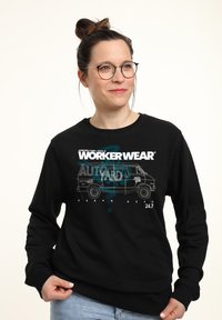 Svart sweatshirt med en framträdande grafisk design av en skåpbil och text. Långa ärmar, rundad halsringning och mjukt tyg. Stl. synligt medium.
