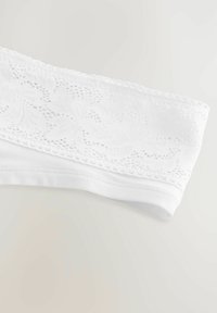 Bande blanche sans couture avec un motif floral en dentelle texturée en haut, finie avec un bord élastique lisse. Tissu doux et léger.