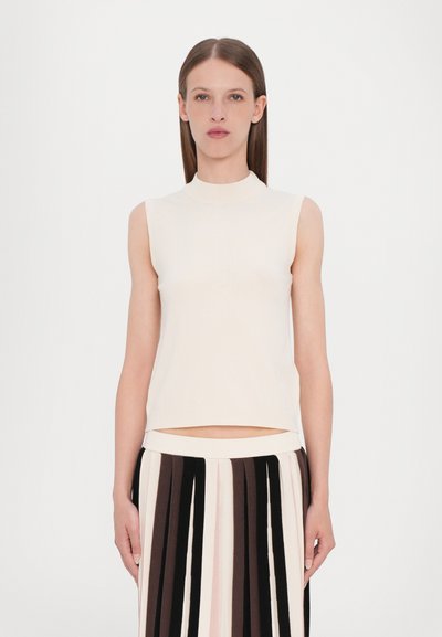 Top senza maniche color crema con collo alto, texture liscia e silhouette aderente, abbinato a una gonna plissettata a righe.