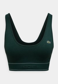 Σκούρο πράσινο ριμπ αθλητικό σουτιέν με φαρδιές τιράντες, λαιμόκοψη scoop και αντίθετη μαύρη επένδυση. Διαθέτει υφασμένη ζώνη με ανάγλυφο το "LACOSTE".