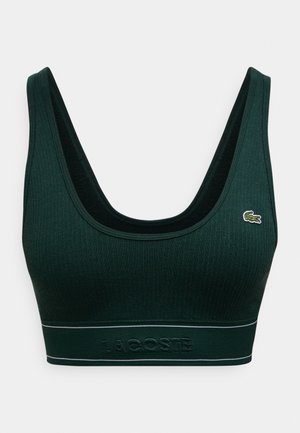 Σκούρο πράσινο ριμπ αθλητικό σουτιέν με φαρδιές τιράντες, λαιμόκοψη scoop και αντίθετη μαύρη επένδυση. Διαθέτει υφασμένη ζώνη με ανάγλυφο το "LACOSTE".