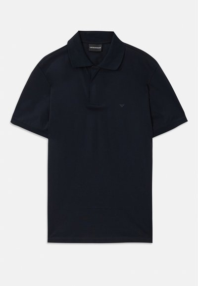 Navy zils īsā piedurkne polo krekls ar apkakli un diskrētu logo kreisajā krūtī, novietots plakaniski uz baltā fona.
