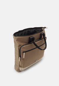 Beige stoffen draagtas met zwarte handvatten, ritssluiting bovenaan en een voorvak met een zwarte rits. Glad textuur en rechthoekige vorm.