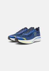 Zilās sporta kurpes ar acs augšējo daļu, teksturētu rakstu, melnām akcentiem un baltu zoli ar zaļām un dzeltenām svītrām.