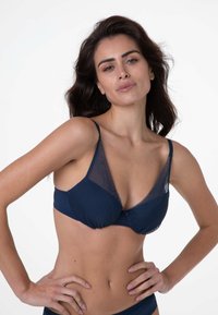Reggiseno blu navy con dettagli in pizzo e design testurizzato. Presenta spalline regolabili e chiusura a gancio. Coppe femminili a forma di V.