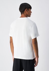 Camiseta de algodón blanca de manga corta, con cuello redondo y corte regular. Textura suave, sin patrones ni adornos visibles.