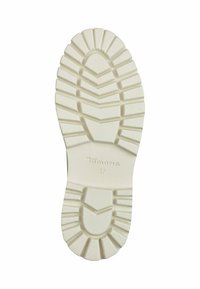 Semelle de chaussure en caoutchouc blanc avec un motif de bande de profondeur et de crêtes. Marquée "Tamaris" et taille "37" sur la surface.