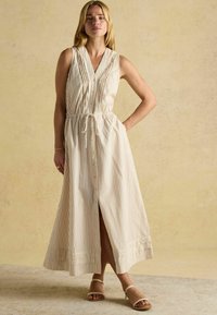 Pruhované bezrukávové maxi šaty v jemnej béžovej a krémovej farbe, s pásom na stiahnutie, gombíkovou légou a rozparkom na leme.