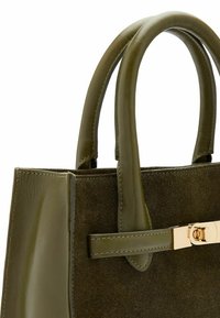 Olijfgroene handtas met een combinatie van gladde leder en suède texturen, voorzien van ronde handvatten en een gouden hardware accent.