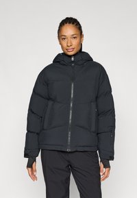 Schwarze Steppjacke mit Reißverschluss vorne, Kapuze und gerippten Bündchen. Verfügt über ein gestepptes Design und eine zusätzliche Reißverschlusstasche an der Seite.