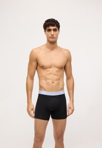 Čierne boxerky s mäkkým elastickým pásom, na ktorom je šedé logo "Calvin Klein". Tkanina je hladká a priliehavá, s minimalistickým dizajnom.