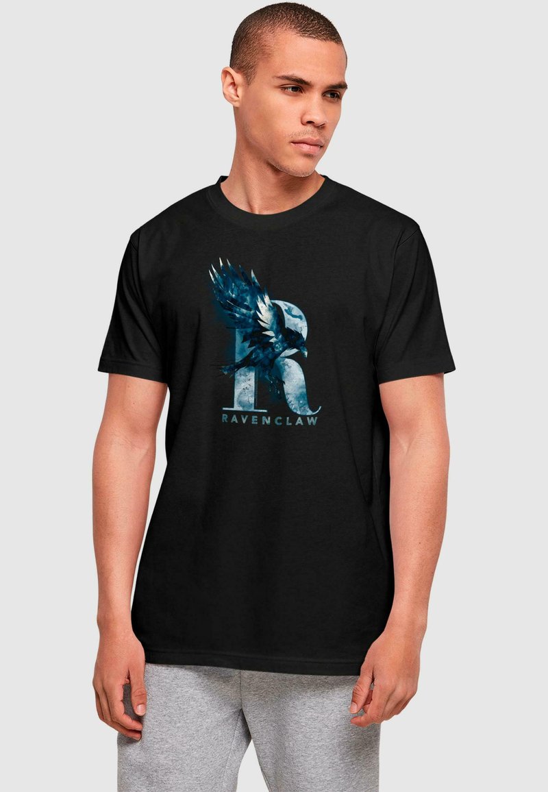 Sort bomulds T-shirt med et blåt og hvidt Ravenclaw emblem, der viser en ørn og bogstavet "R", korte ærmer og rund halsudskæring.