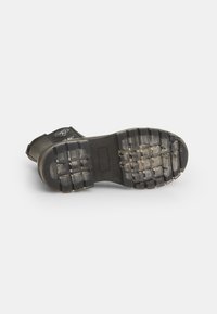 Guma podplata čizme s teksturiranim vzorcem, v črno-sivi barvni shemi in logotipom na strani.