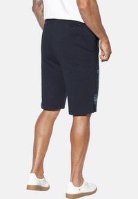 Marineblaue Baumwollshorts mit elastischem Bund, seitlichen Taschen und einer Gesäßtasche. Mit einem Logo-Schriftzug auf dem Oberschenkel.