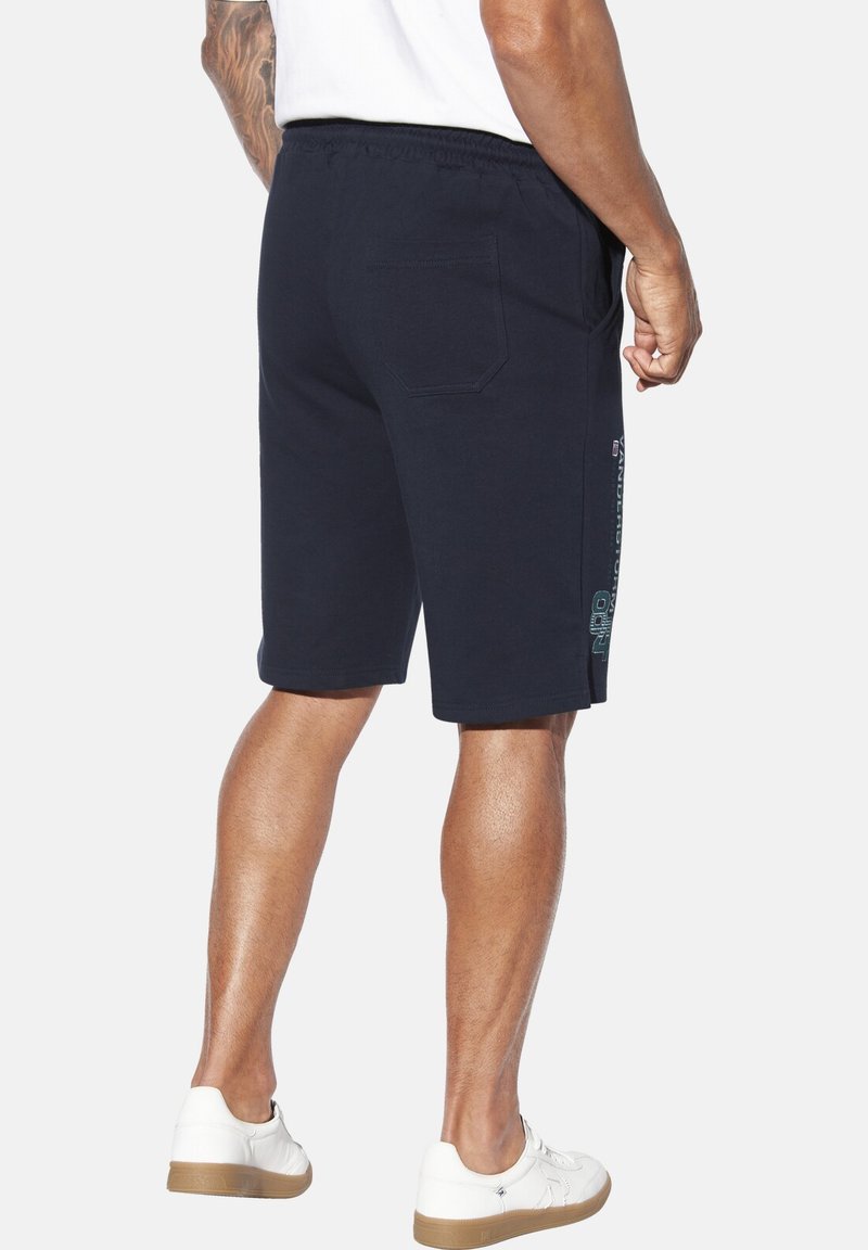 Marineblaue Baumwollshorts mit elastischem Bund, seitlichen Taschen und einer Gesäßtasche. Mit einem Logo-Schriftzug auf dem Oberschenkel.