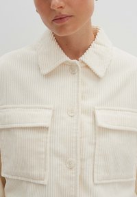 Cremfarbener Corduroy-Hemdjacke mit Kragen, zwei Brusttaschen und Knopfverschlüssen. Verfügt über eine gerippte Textur und dezente Nähte.