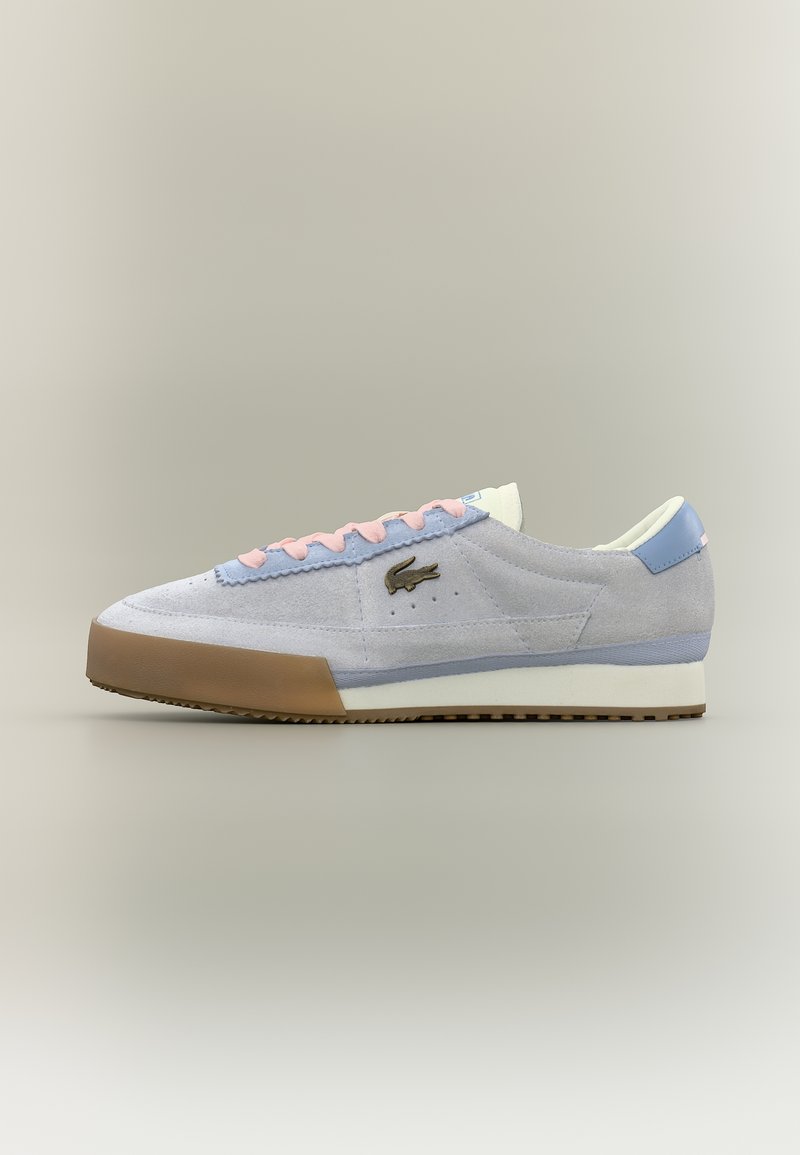 Ανοιχτό γκρι σουέντ αθλητικό παπούτσι με παστέλ μοβ και ροζ λεπτομέρειες, καφέ λαστιχένια μύτη, λευκή σόλα και κεντητό σκούρο πράσινο λογότυπο κροκοδείλου.