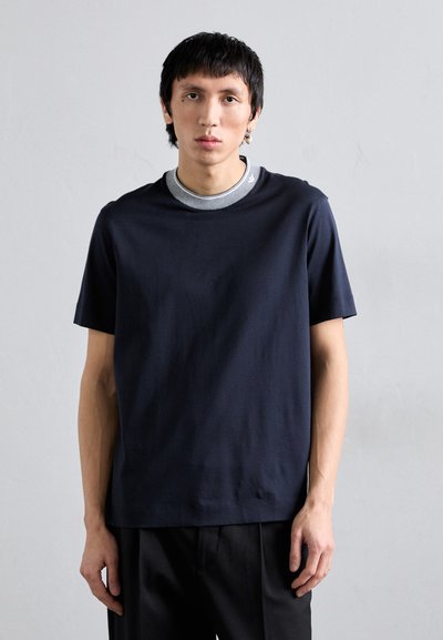 T-shirt in cotone blu navy con scollo rotondo e maniche corte. Presenta un colletto grigio a strati sotto. Texture liscia, vestibilità casual.
