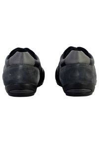 Chaussures en cuir noires et grises avec une texture lisse, talon arrondi et semelle en caoutchouc. Design minimal avec des accents élastiques visibles.