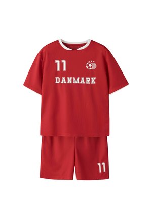 Czerwona koszulka i spodenki piłkarskie z białym obszyciem, numer 11 na koszulce i spodenkach, napis „DANMARK” oraz logo piłki nożnej z gwiazdkami na przodzie koszulki.