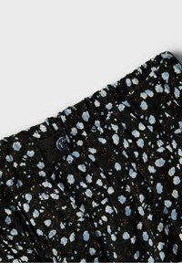 Tela negra con un patrón floral que presenta flores en azul claro y blanco. Superficie texturizada con una cinturilla fruncida y detalle de cierre con botón.