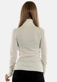 Pullover color crema con collo alto, polsini e orlo a coste, e spalle a sbuffo, realizzato in morbido materiale lavorato a maglia.