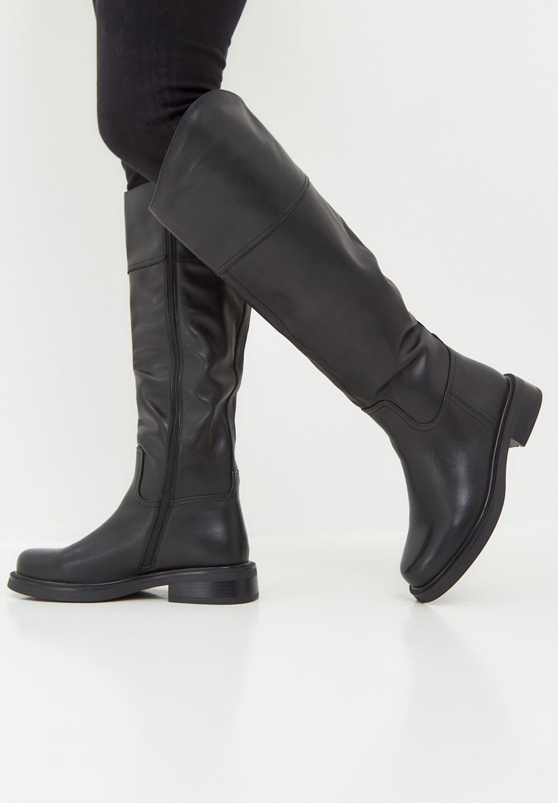 Black knee-high boots made of smooth leather, featuring a rounded toe, low block heel, and side zipper detail. Subtle stitching accents present.